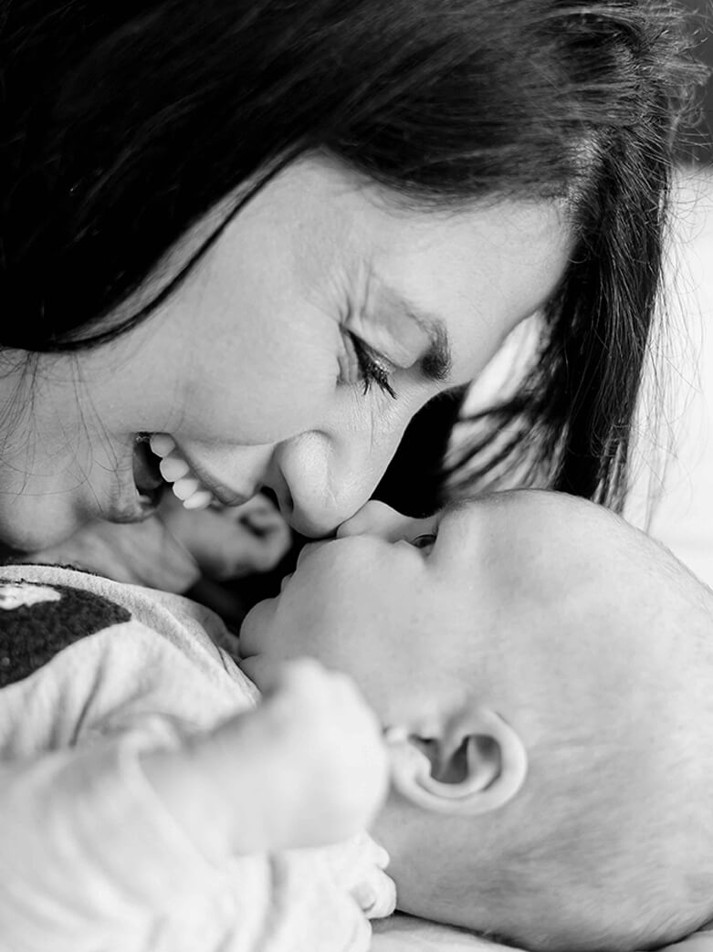 newborn films and photos: baby boy looking at his mum and touching noses. Mum is laughing.