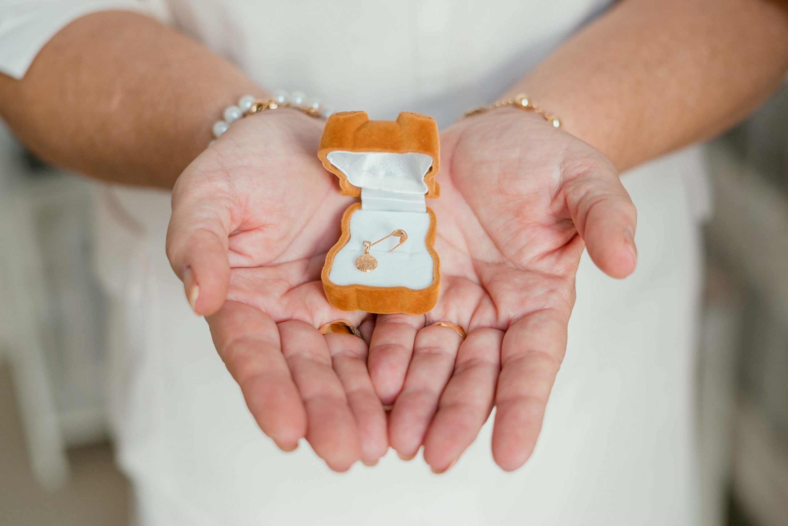 newborn films and photos: close up of grandma with baby's jewellery in her hands
